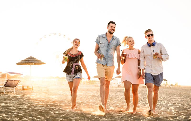 Gruppe geht im Ibiza Urlaub mit Kindern am Strand spazieren