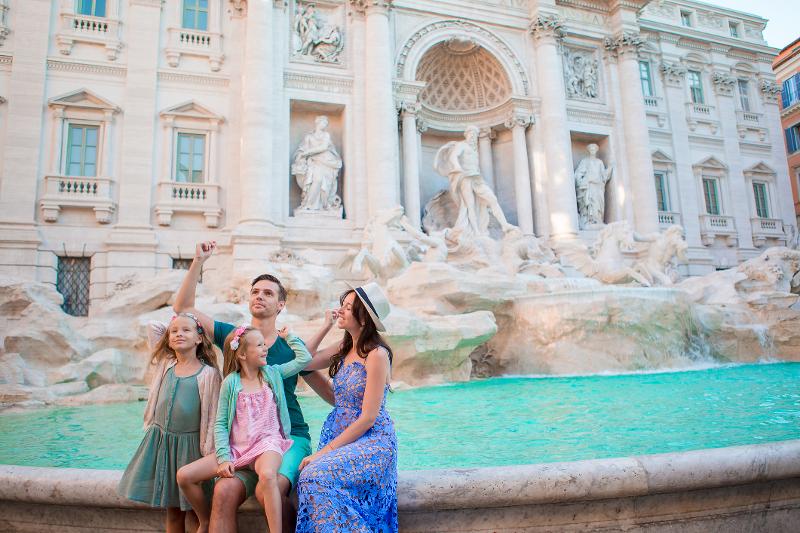  Eine Familie sitzt gemeinsam am Trevibrunnen im Italien Urlaub mit Kindern am Meer All Inclusive