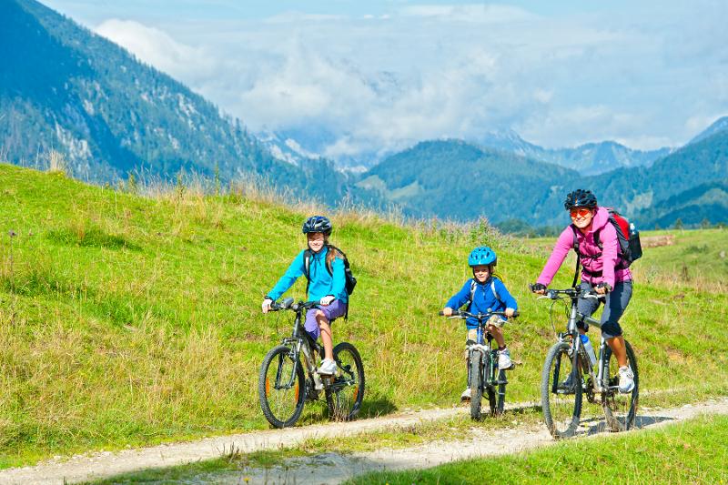  Eine Familie fährt auf Fahrrädern durch eine Berglandschaft.