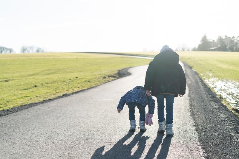 Mutter und Kinder wandern auf einem Weg durch eine weite Landschaft, wo sie einen Gegenstand auffinden