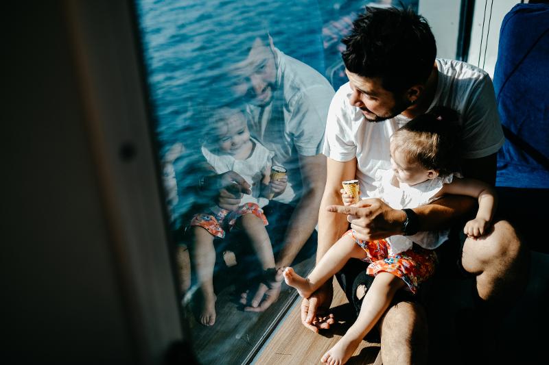 Vater und Kind schauen aus dem Fenster eines Kreuzfahrtschiffes auf das Meer