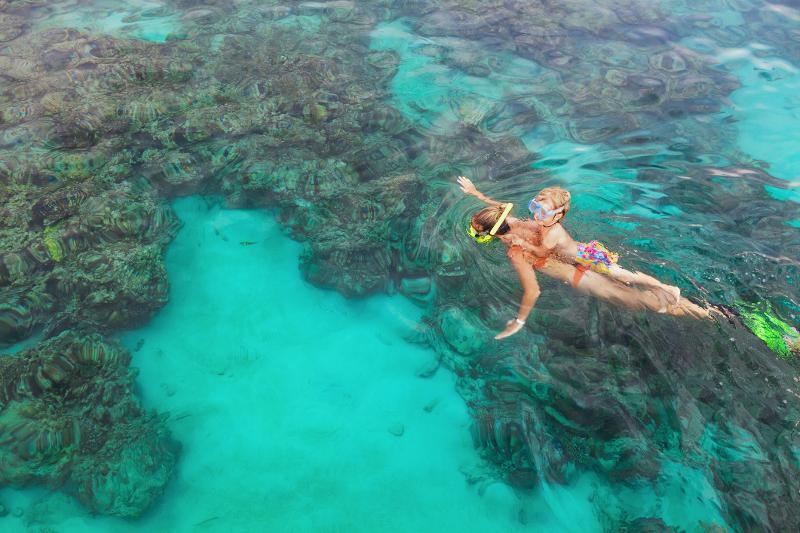Mutter und Kind schnorcheln und erkunden die Unterwasserwelt im klaren blauen Meer