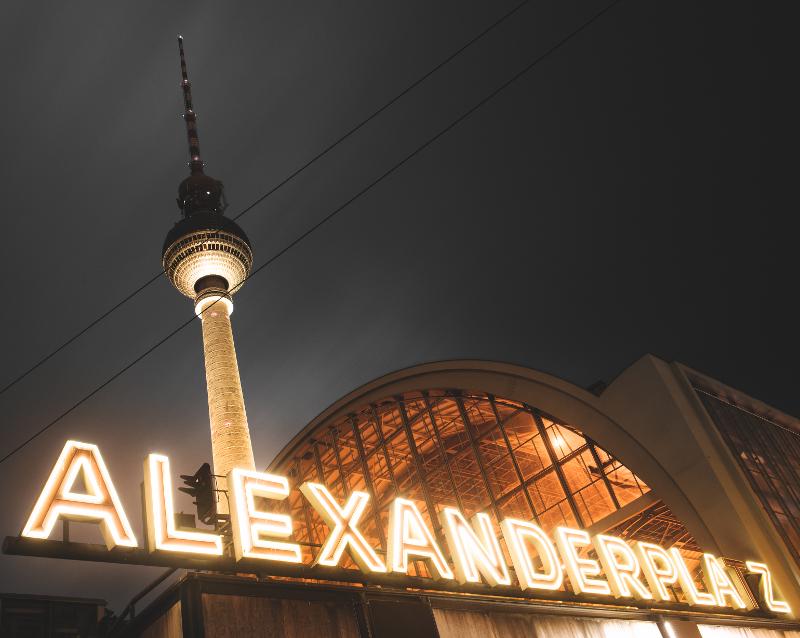 Ausblick auf die erleuchtete U-Bahnstation Alexanderplatz bei Nacht mit dem Fernsehturm im Hintergrund im Kurztrip Berlin mit Kindern