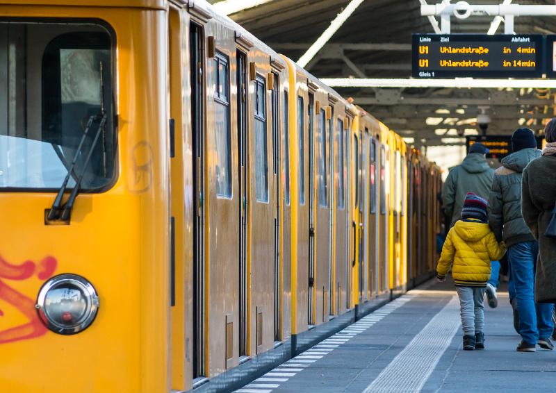 Eine gelbe Bahn an einem Bahnsteig mit Menschen im Kurztrip Berlin mit Kindern