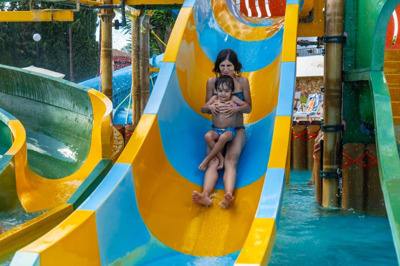  Ein Junge sitzt auf dem Schoß seiner Mama auf einer Wasserrutsche im Last Minute Familienurlaub Mallorca 