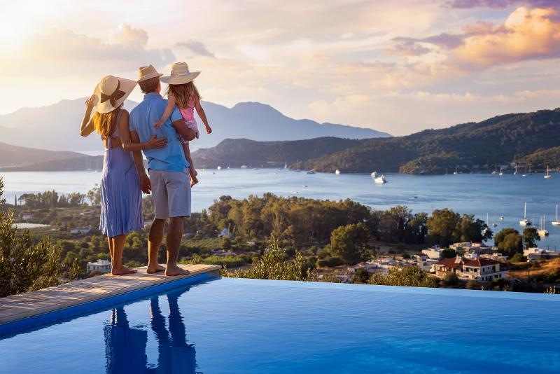 Familie steht neben einem Panorma Pool und schaut in die Landschaft auf einen See