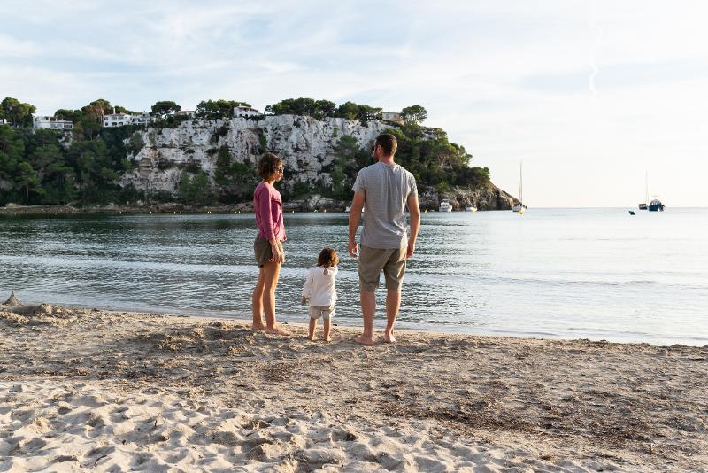 Eltern und Kind stehen im Menorca Urlaub mit Kindern All Inclusive am Strand
