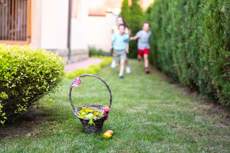 Kinder rennen auf ein Osterkorb mit Ostereiern zu-tag