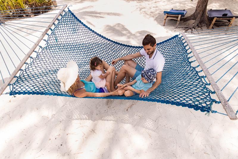 Eine Familie entspannt in einer Hängematte am Strand.