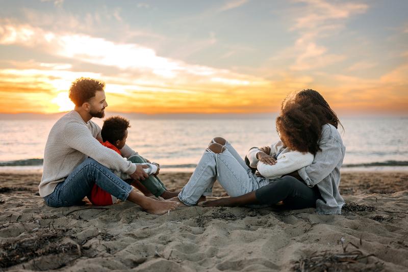 Familie schaut am Strand den Sonnenuntergang