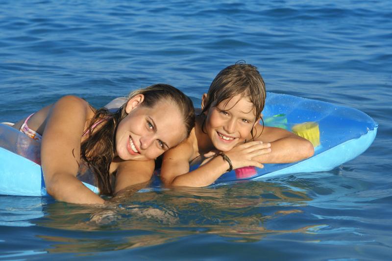 Zwei Kinder sind bei Reisen mit Kindern Mallorca auf Luftmatratzen im Wasser