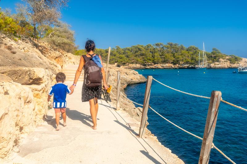Mutter und Sohn spazieren bei Reisen mit Kindern Mallorca am Meer entlang