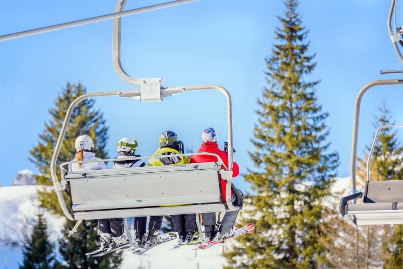 Vier Personen auf einem Skilift im Skiurlaub Österreich mit Kindern