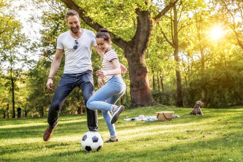 Vater und Tochter spielen Fußball im Sommerurlaub mit Kindern