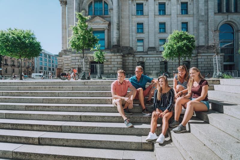 Familie sitzt auf Steintreppen in einer Stadt im Sommerurlaub mit Kindern