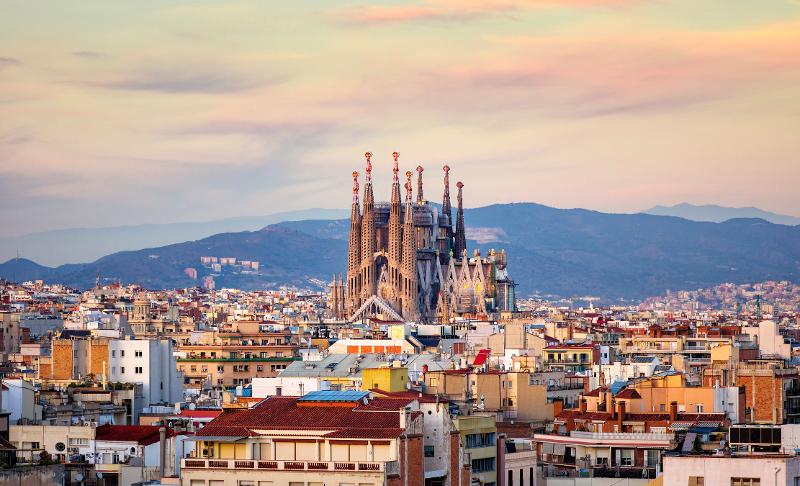 Aussicht auf eine Kathedrale in Barcelona im Spanien Urlaub mit Kindern All Inclusive mit vielen Häusern und Bergen bei Sonnenuntergang
