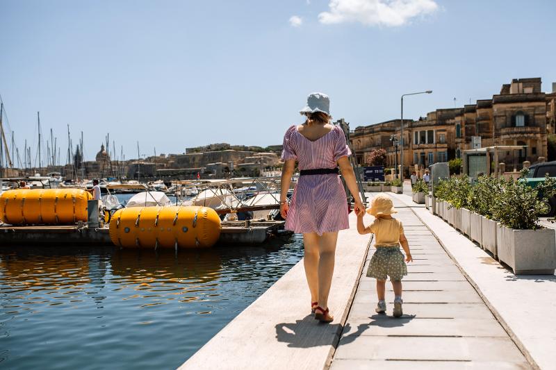 Mutter und Kind laufen auf einer Familiensprachreise an einem Hafen entlang