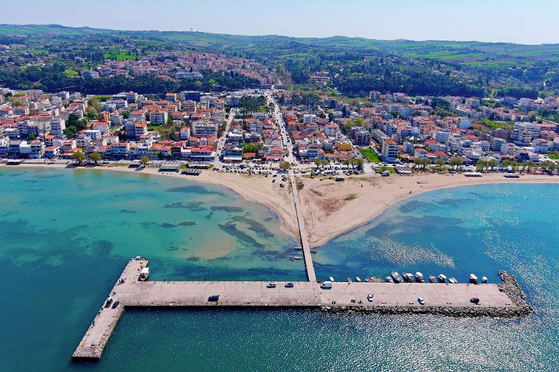 Vogelperspektive auf einen langen Steg mit Autos und die Stadt am Meer im Thessaloniki Urlaub mit Kindern