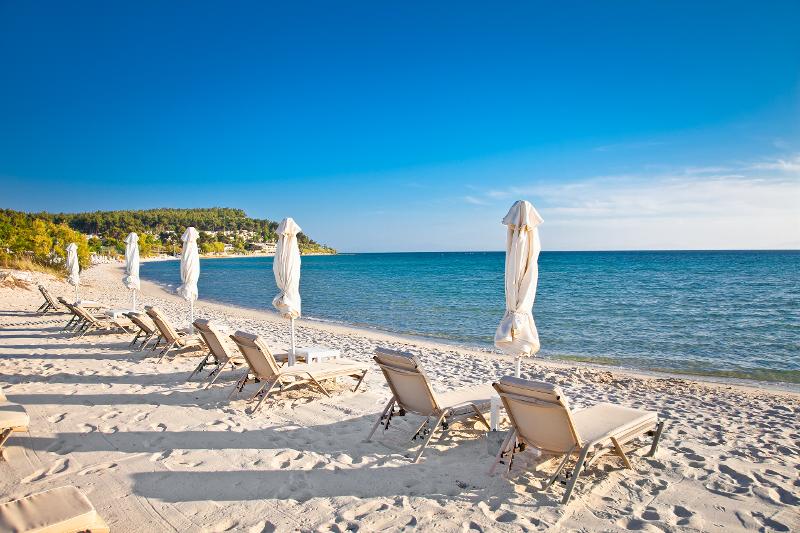 Weißer Sandstrand und klares Meer mit Sonnenliegen und Sonnenschirmen im Thessaloniki Urlaub mit Kindern