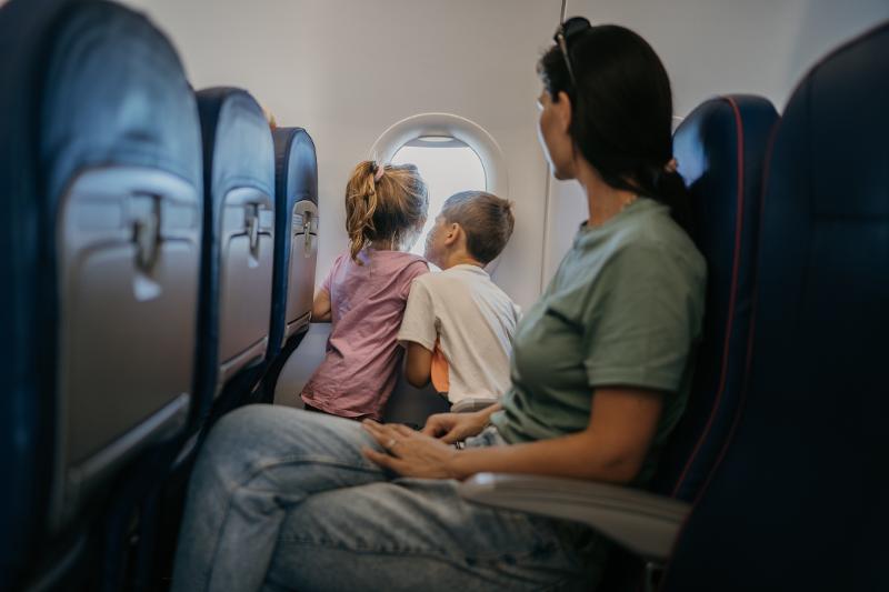 Eine Mutter und zwei Kinder im Flugzeug, auf dem Weg in den Urlaub in Großbritannien mit Kindern