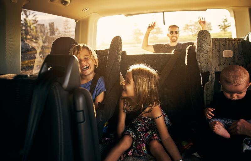  Lachende Kinder sitzen im Auto auf dem Weg in den Urlaub in Italien mit Kindern und Auto