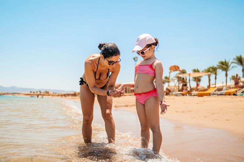 Eine Mutter badet gemeinsam am Strand mit ihrem Kind im Urlaub mit Kindern Ägypten 
