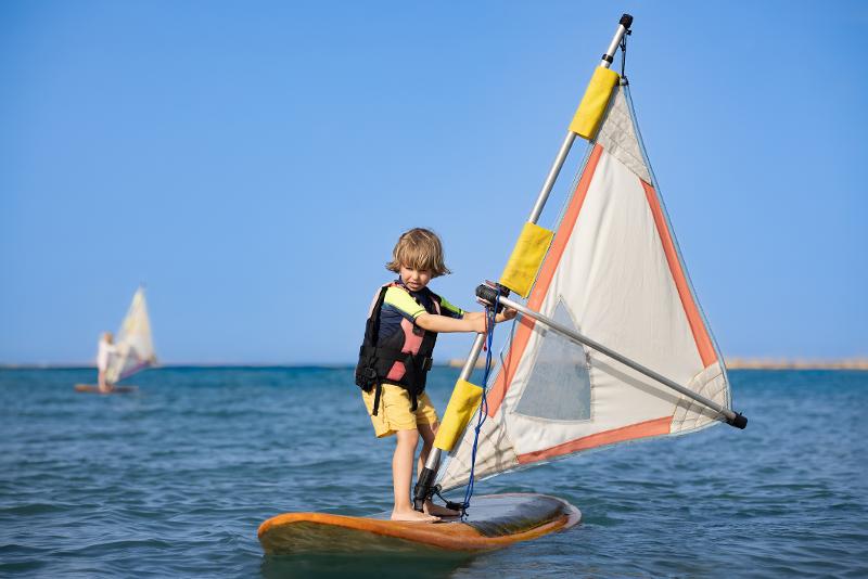 Ein Kind steht auf einem Windboard im Urlaub mit Kindern Ägypten 