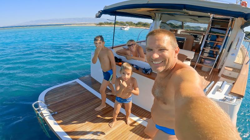 Familie genießt ihren Urlaub mit Kindern All Inclusive auf einem Boot mit klarem, blauem Wasser im Hintergrund.