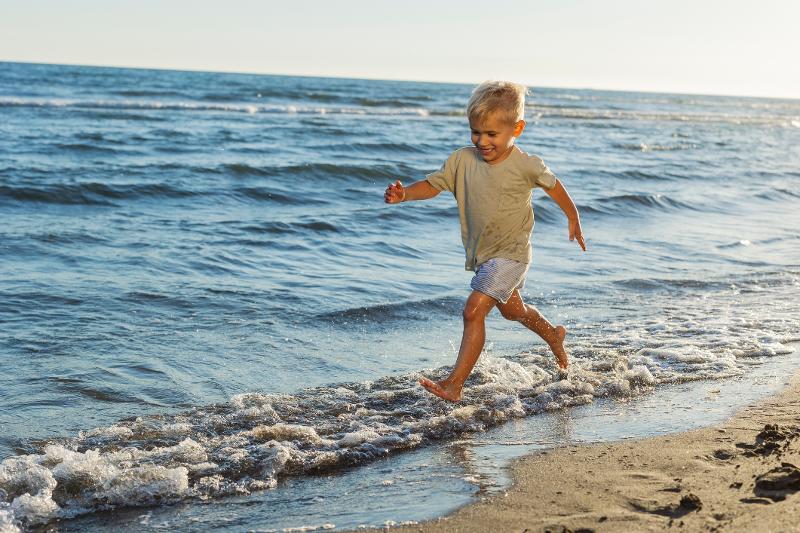 Ein Junge läuft im Urlaub mit Kindern Menorca über den Strand