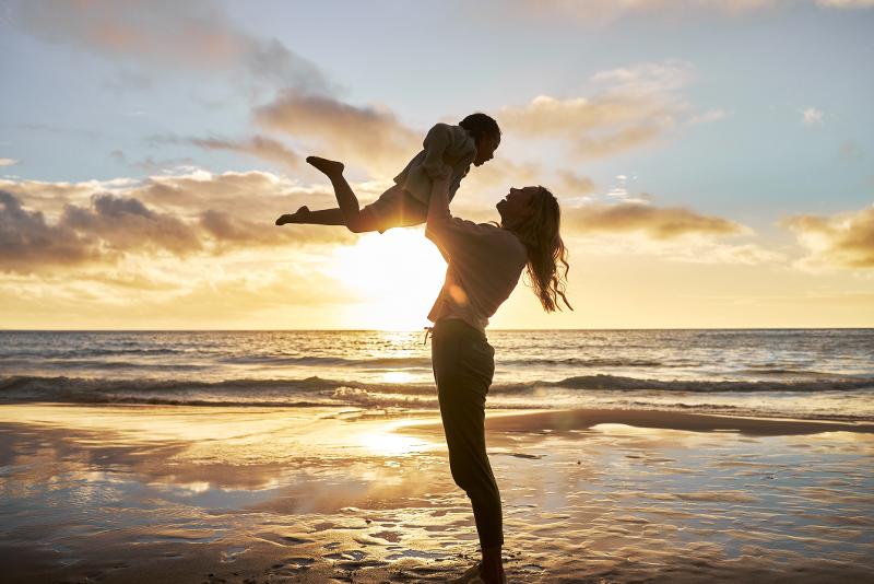 Mutter hebt ihr Kind im Urlaub mit Kindern Balearen hoch