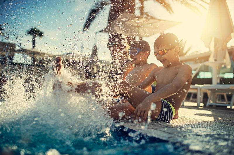 Kinder sitzen am Pool und planschen