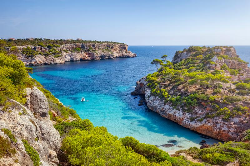 Aussicht von einem Felsen auf eine Bucht mit blauem Meer, grünen Baumkronen und verschiedenen Felsformationen im Urlaub mit Kindern Europa Strand