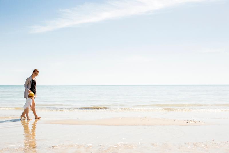  Eine Mutter spaziert mit ihrem Kind am Strand im Urlaub mit Kindern in Italien am Meer günstig