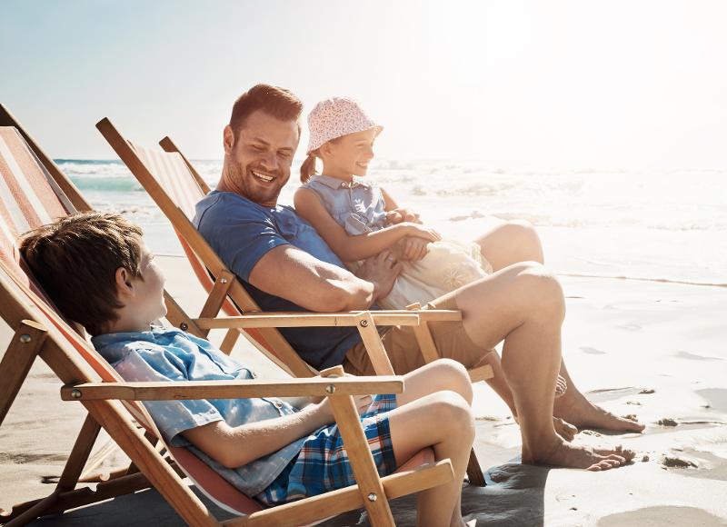 Eine Familie, die im Urlaub mit Kindern Zypern in Sonnenstühlen am Strand sitzt