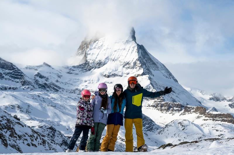 Ein glückliches Familienbild einer vierköpfigen Familie vor einer Schneebedeckten Berglandschaft