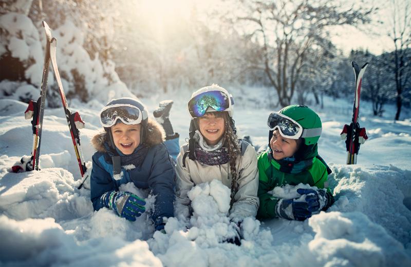 Drei Kinder, die glücklich im Schneeliegen