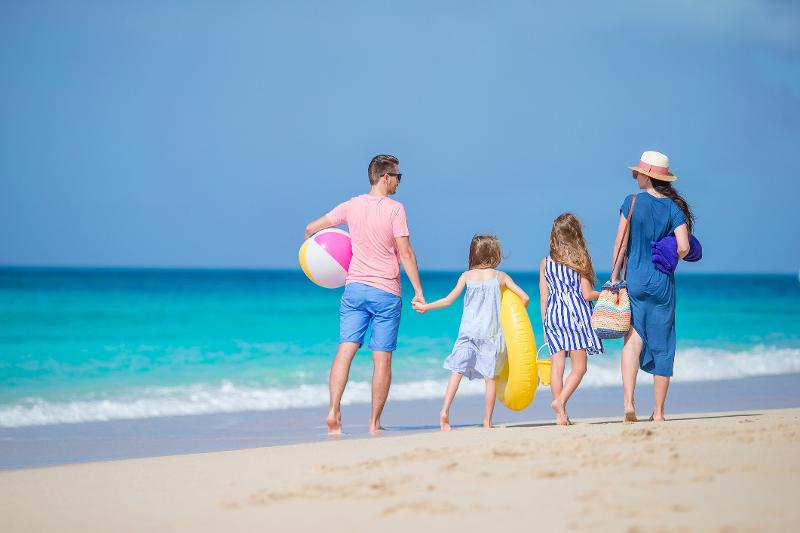 Eine Familie, die im Zakynthos Urlaub mit Kindern einen Strandspaziergang am Strand macht