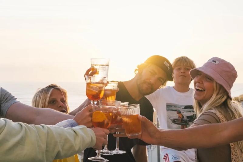 Familie stößt mit Getränken an auf Familienreise Surfen