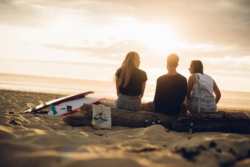 Drei junge Menschen am Strand mit ihren Surfboards im Familienurlaub Portugal