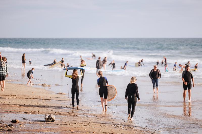 viele Surfer am Strand.Im Hintergrund befindet sich der Ozean