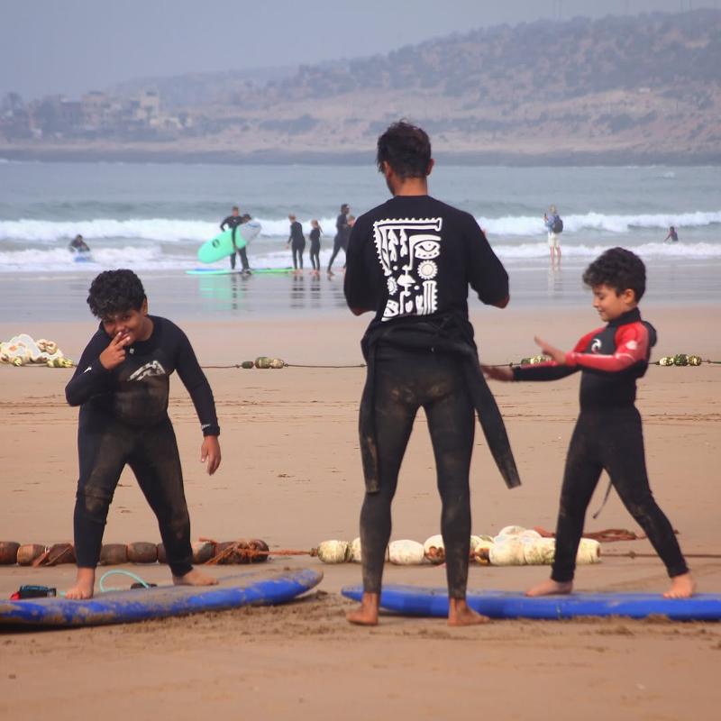 Zwei Kinder lernen mit dem Surfcoach das surfen am Strand