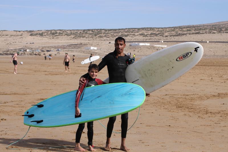 Surfcoach steht mit Schüler am Strand mit Surfboards
