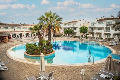 Runder Pool mit Palmeninsel und flachen Hotelgebäuden im Familienurlaub Mallorca