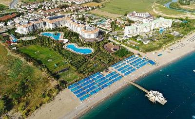 Große Hotelanlage mit zwei großen Pools und Strandbereich mit Liegen im Familienurlaub Türkei