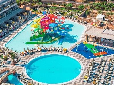 Runder Pool neben Splashpool und bunten Wasserrutschen im Familienurlaub Kreta