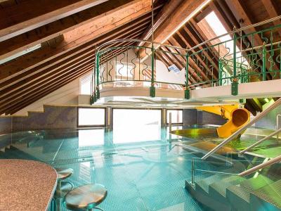 Gemütliches Hallenbad mit gelber Wasserrutsche im Familienurlaub Österreich
