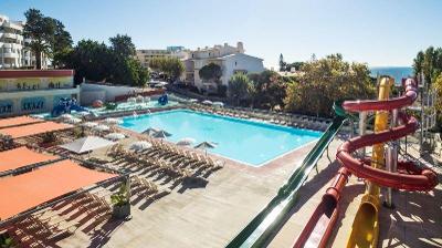 Pool mit Sonnenliegen und mehreren bunten Wasserrutschen im Familienurlaub Portugal