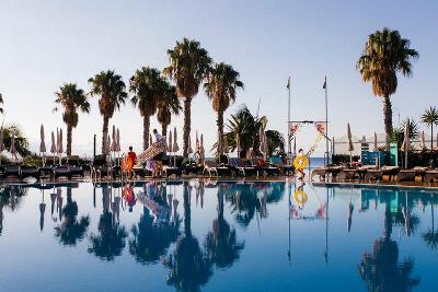 Palmen spiegeln sich im Pool und Kinder haben Schwimmringe im Familienurlaub Madeira