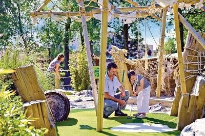 Vater und Kind spielen auf einer Minigolfanlage im Familienurlaub Niederlande