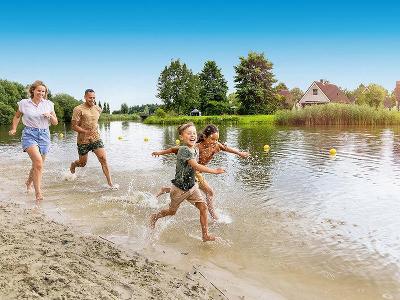 Familie rennt durchs Wasser im Familienurlaub Niederlande